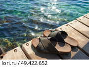 A pair of mens leather sandals on water’s edge by sea. Стоковое фото, агентство Ingram Publishing / Фотобанк Лори