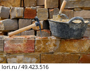 Masonry stone wall construction with mortar and brick hammer trowel tools DIY. Стоковое фото, агентство Ingram Publishing / Фотобанк Лори