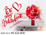 Be my Valentine text lettering with white gift box, red bow on snow with bokeh and snowfall. Valentines day, declaration of love concept. Стоковое фото, агентство Ingram Publishing / Фотобанк Лори