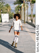 Smiling black woman on roller skates riding outdoors on beach promenade with palm trees. Smiling girl with afro hairstyle rollerblading on sunny day. Стоковое фото, агентство Ingram Publishing / Фотобанк Лори