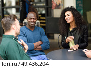 Multiracial group of friends waiting for a coffee together. Two men and a man sitting at cafe, talking and smiling. Lifestyle and friendship concepts with real people models. Multiracial group of friends waiting for a coffee together. Стоковое фото, агентство Ingram Publishing / Фотобанк Лори