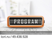 Program message on a retro clock in orange on a wooden table in bright light. Стоковое фото, агентство Ingram Publishing / Фотобанк Лори