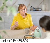 Upset adult and young woman drinking tea in kitchen. Стоковое фото, фотограф Яков Филимонов / Фотобанк Лори