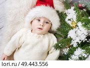 Relaxed little santa boy lying next to the pine. Стоковое фото, агентство Ingram Publishing / Фотобанк Лори