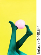 Green legs of a woman holding a pink balloon against a yellow wall                               . Стоковое фото, агентство Ingram Publishing / Фотобанк Лори