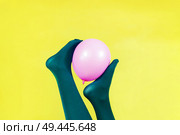 Green legs of a woman holding a pink balloon against a yellow wall                               . Стоковое фото, агентство Ingram Publishing / Фотобанк Лори
