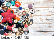 Spools of threads and buttons on wooden table. Buttons and threads with needle. Стоковое фото, агентство Ingram Publishing / Фотобанк Лори