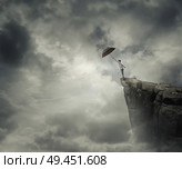 Boy trying to catch his umbrella on the edge of a cliff above the clouds. Escape and fly away. Стоковое фото, агентство Ingram Publishing / Фотобанк Лори