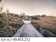 Crystal ball in balance on a wooden log in the nature by a lake. Стоковое фото, агентство Ingram Publishing / Фотобанк Лори