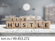 Side hustle sign on a plank table in a decorative room with a clock. Стоковое фото, агентство Ingram Publishing / Фотобанк Лори