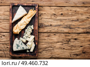 Wooden board with different kinds of delicious cheese.Piece of cheese. Delicious cheese on the table. Стоковое фото, агентство Ingram Publishing / Фотобанк Лори