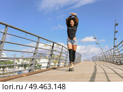 Black woman, afro hairstyle, on roller skates riding outdoors on urban bridge with open arms. Smiling young female rollerblading on sunny day. Beautiful clouds in the sky.. Afro hairstyle woman on roller skates riding outdoors on urban bridge. Стоковое фото, агентство Ingram Publishing / Фотобанк Лори