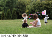 A family with three children. A mother with many children and toddlers in a summer park. Children are walking and flying a kite. Large families, family values, and leisure time with children. Стоковое фото, фотограф Photojuli / Фотобанк Лори