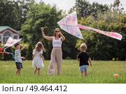 A family with three children. A mother with many children and toddlers in a summer park. Children are walking and flying a kite. Large families, family values, and leisure time with children. Стоковое фото, фотограф Photojuli / Фотобанк Лори