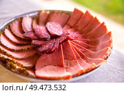 Cold smoked meat plate with sliced prosciutto, salami, bacon, pork chops. Different kinds of meat cuts on the boards. Meat antipasto platter. Traditional Belorussian cuisine. Стоковое фото, агентство Ingram Publishing / Фотобанк Лори