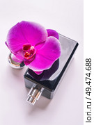 black fragrance  bottle with purple orchid around white. flat lay. Стоковое фото, агентство Ingram Publishing / Фотобанк Лори