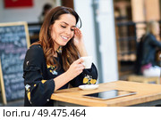 Middle-aged woman drinking coffee in an urban cafe bar. Young female sitting at table at an outside terrace. Girl with california highlights hairstyle.. Middle-aged woman drinking coffee in an urban cafe bar. Стоковое фото, агентство Ingram Publishing / Фотобанк Лори