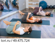 Young woman performing Pawanmuktasana during group yoga training. Стоковое фото, фотограф Яков Филимонов / Фотобанк Лори