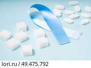 Sugar cubes, Diabetes Awareness Blue Ribbon and pills on plain blue background. World Diabetes Day concept.. Sugar on blue background. Стоковое фото, агентство Ingram Publishing / Фотобанк Лори