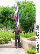 A man in military uniform raises the flag of the Kingdom of Thailand in the public green park Chatuchak, Bangkok, Thailand (2024 год). Редакционное фото, фотограф Коханова Наталья / Фотобанк Лори