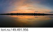 Panoramic view of colorful sunset clouds symmetric reflected on the lake surface. Idyllic summer evening, natural scene near a countryside pond with calm water. Стоковое фото, агентство Ingram Publishing / Фотобанк Лори