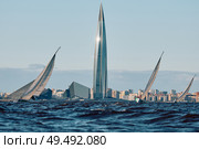 Russia, St.Petersburg, 01 June 2025: Sailing regatta in the Gulf of Finland at sunset, hot race of several yachts, teamwork, yachtsmen sitting on board the boat. Редакционное фото, фотограф Vladimir Drozdin / Фотобанк Лори