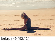 Caucasian woman practicing yoga at seashore. Young female doing fitness legs split on sand in the beach in Cadiz, Andalusia, Spain.. Caucasian blonde woman practicing yoga in the beach. Стоковое фото, агентство Ingram Publishing / Фотобанк Лори