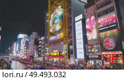 Osaka, Japan - Sep 22 2024, 4k, Panoramic view of Dotonbori river with a ship with tourists, a lot of people on embankment, there are a lot of advertising and illuminations on buildings, Osaka, Japan. Редакционное видео, видеограф Сергей Богомяко / Фотобанк Лори