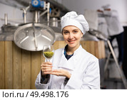 Successful female brewmaster showing hop pellets in glass. Стоковое фото, фотограф Яков Филимонов / Фотобанк Лори