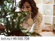 Woman decorating Christmas Tree at home - Winter Season. Стоковое фото, агентство Ingram Publishing / Фотобанк Лори