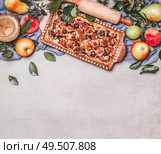 Seasonal garden fruits pie with rolling pin, ingredients, branches and leaves on gray background, top view. Border. Copy space for your design. Horizontal. Стоковое фото, агентство Ingram Publishing / Фотобанк Лори