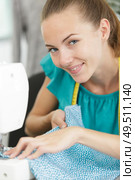 smily young woman sewing with sewing machine. Стоковое фото, агентство Ingram Publishing / Фотобанк Лори