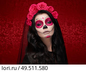 Portrait of a woman with sugar skull makeup over red background. Halloween costume and make-up. Portrait of Calavera Catrina. Стоковое фото, агентство Ingram Publishing / Фотобанк Лори