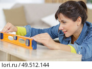 a handywoman behind a level. Стоковое фото, агентство Ingram Publishing / Фотобанк Лори