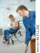 boyfriend helping wheelchair girlfriend to do hoovering. Стоковое фото, агентство Ingram Publishing / Фотобанк Лори