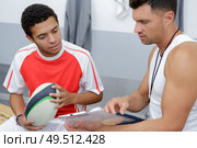young player talking game strategy with coach in changing room. Стоковое фото, агентство Ingram Publishing / Фотобанк Лори