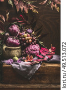 Still life with purple fruits and vegetables on wooden table with crockery, napkin and autumn leaves . Copy space for your design. Стоковое фото, агентство Ingram Publishing / Фотобанк Лори