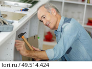senior man assembling kitchen base units. Стоковое фото, агентство Ingram Publishing / Фотобанк Лори