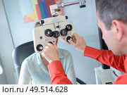 female patient looking through phoropter during eye exam. Стоковое фото, агентство Ingram Publishing / Фотобанк Лори