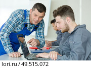 teacher pointing at a program on the trainees laptop. Стоковое фото, агентство Ingram Publishing / Фотобанк Лори