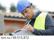 concentrated builder using a clipboard outdoors. Стоковое фото, агентство Ingram Publishing / Фотобанк Лори