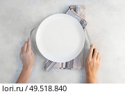 Abstract food background - empy white plate with someones hands holding cutlery. Abstract food background. Стоковое фото, агентство Ingram Publishing / Фотобанк Лори