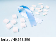 Sugar cubes, Diabetes Awareness Blue Ribbon and pills on plain blue background. World Diabetes Day concept.. Sugar on blue background. Стоковое фото, агентство Ingram Publishing / Фотобанк Лори