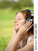 Portrait of the beautiful girl listening to music in ear-phones in park. Стоковое фото, агентство Ingram Publishing / Фотобанк Лори