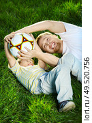 Daddy and son struggling for a ball on a lawn. Стоковое фото, агентство Ingram Publishing / Фотобанк Лори