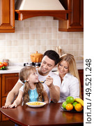 The father feeds the daughter from a spoon with a breakfast. Стоковое фото, агентство Ingram Publishing / Фотобанк Лори