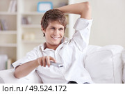 A smiling man changes channels control. Стоковое фото, агентство Ingram Publishing / Фотобанк Лори