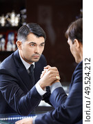 Two men of average years in suits have crossed hands. Стоковое фото, агентство Ingram Publishing / Фотобанк Лори