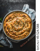 Turkish cuisine. Savory pie with Phyllo dough in baking pan. Su boregi, burek or borek on dark rustic background. Top view. Стоковое фото, агентство Ingram Publishing / Фотобанк Лори