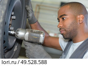 portrait of man mechanic changing tyre. Стоковое фото, агентство Ingram Publishing / Фотобанк Лори